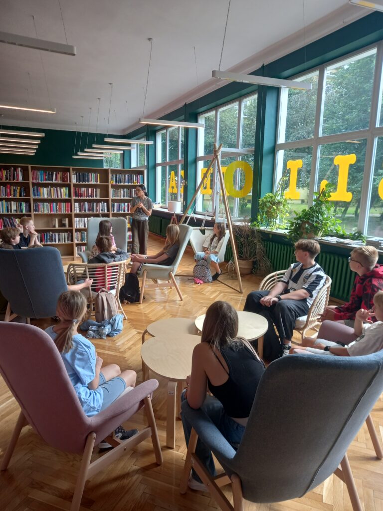 uczniowie siedzą w fotelach w bibliotece