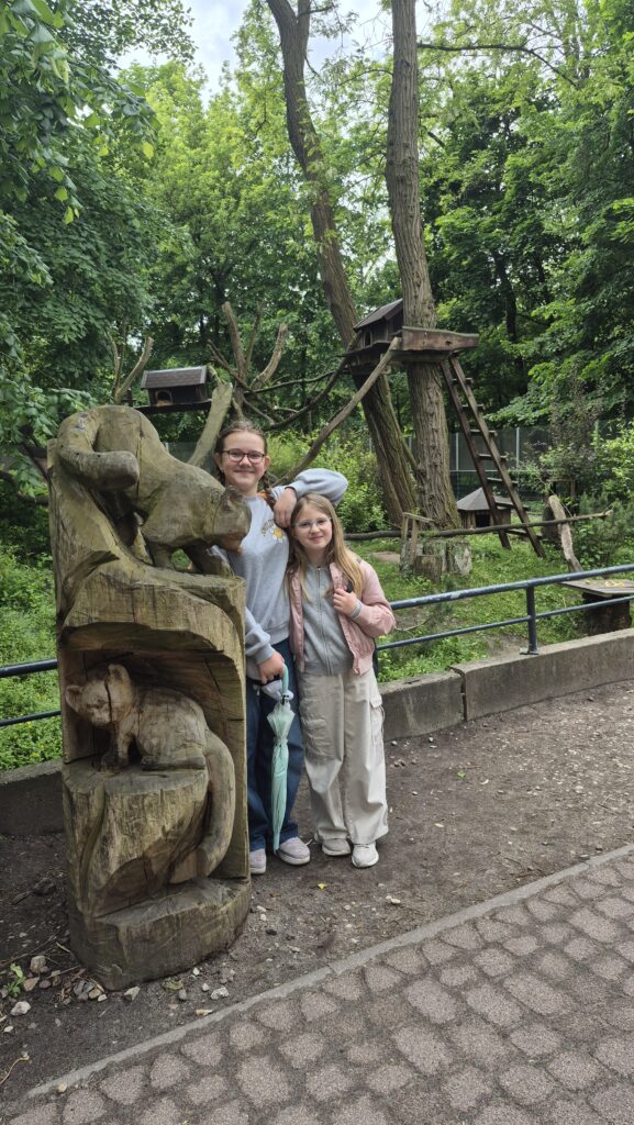 dzieci stoją przy rzeźbie w zoo