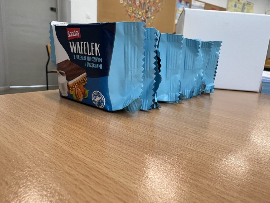 Na ławce stoją w rzędzie zapakowane pojedynczo wafelki.