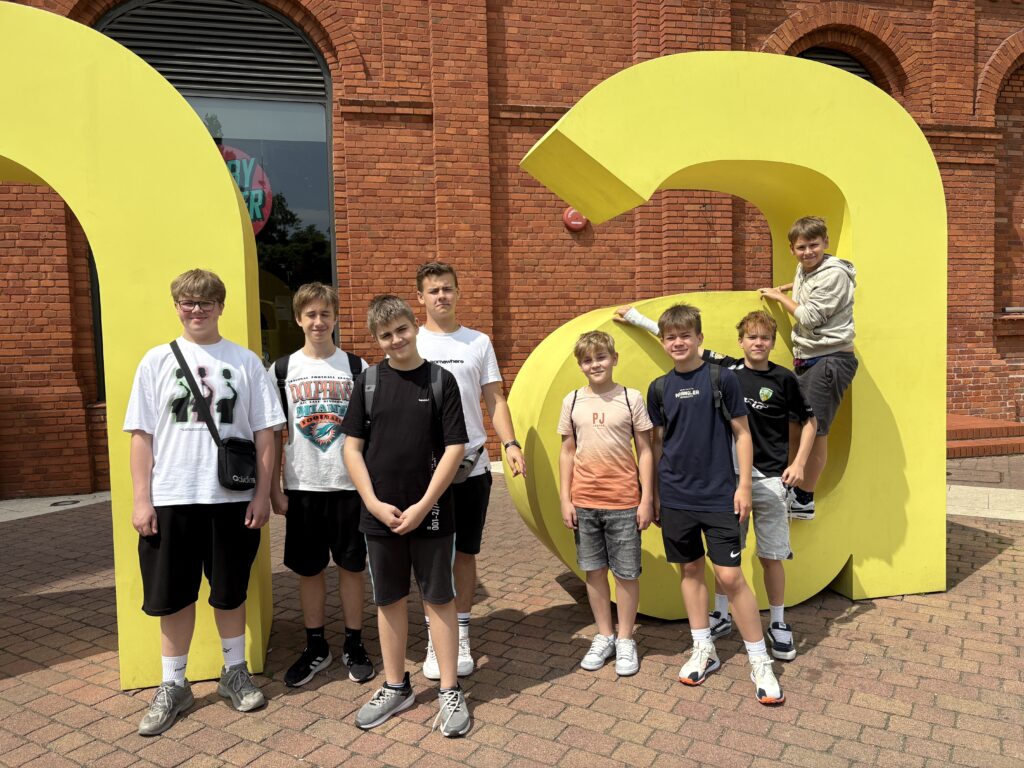 zdjęcie grupowe uczniów przy napisie żółtym manufaktura