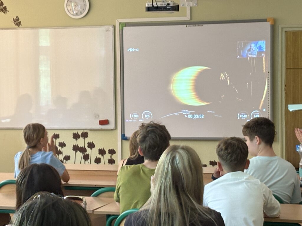 dzieci i pracownicy oglądają na ekranie wylot Sławosza w kosmos, rakieta leci