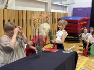 uczniowie wręczają kwiaty storczyki- dyrektorom.