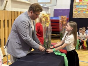 uczniowie wręczają kwiaty storczyki- dyrektorom.