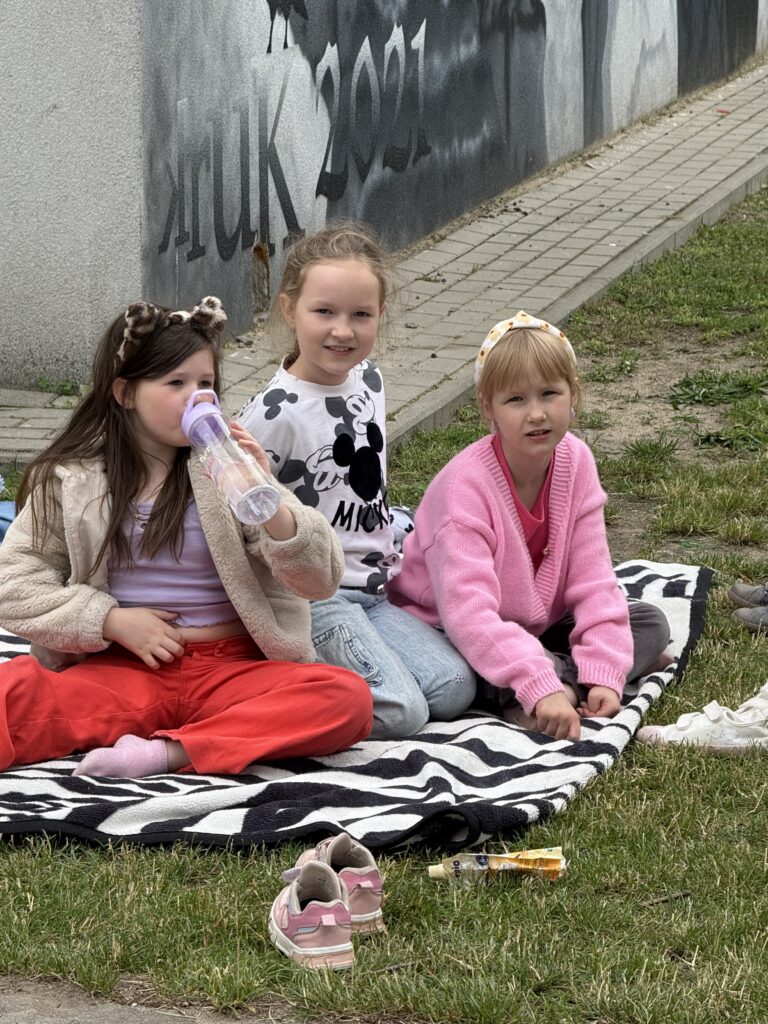 dzieci siedzą na kocyku