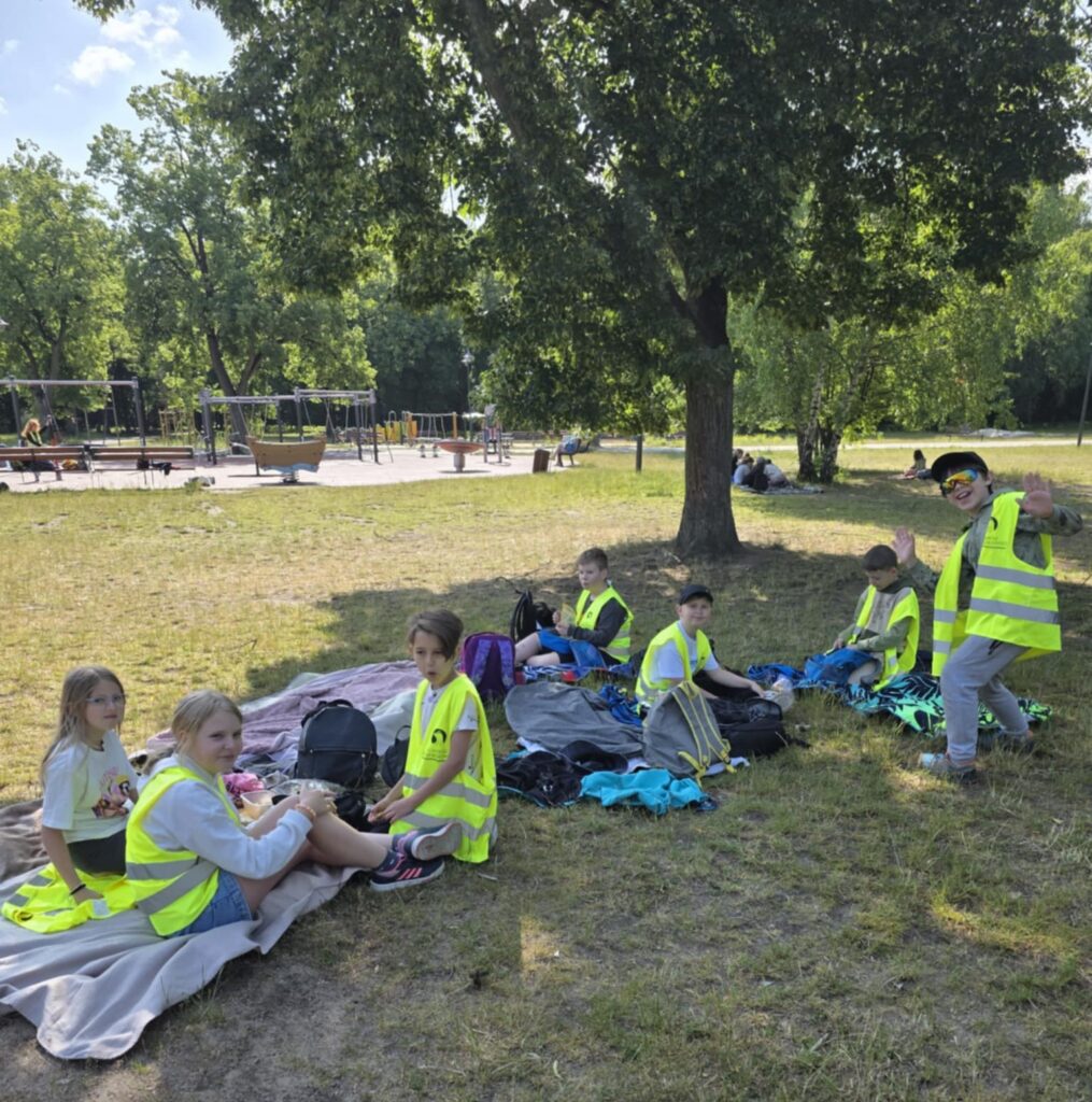 dzieci siedzą uśmiechnięte na trawie
