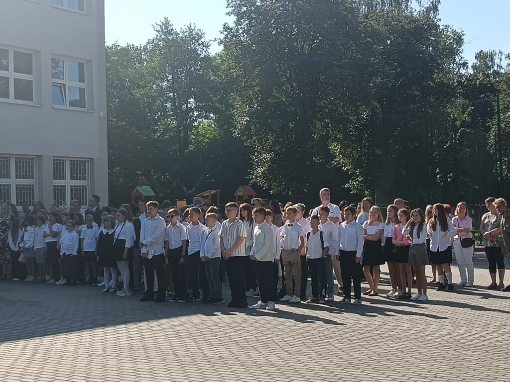zdjęcie grupy uczniów i nauczycieli na apelu szkolnym przed szkołą