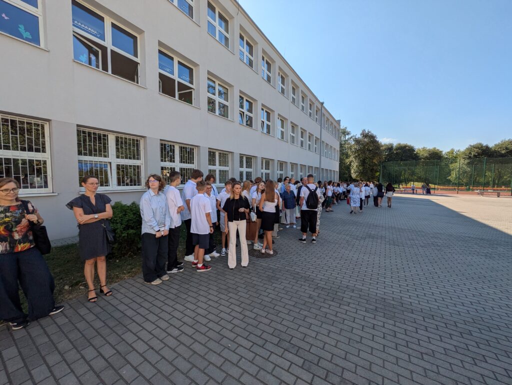 zdjęcie grupy uczniów i nauczycieli na apelu szkolnym przed szkołą
