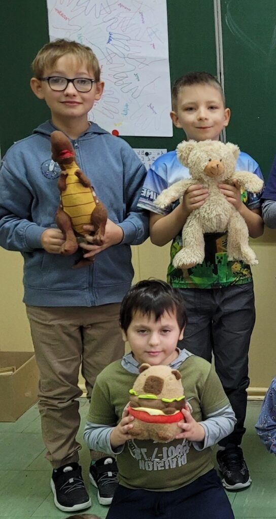trzech chłopców z misiami w rękach, dinozaurem, misiem i chomikiem