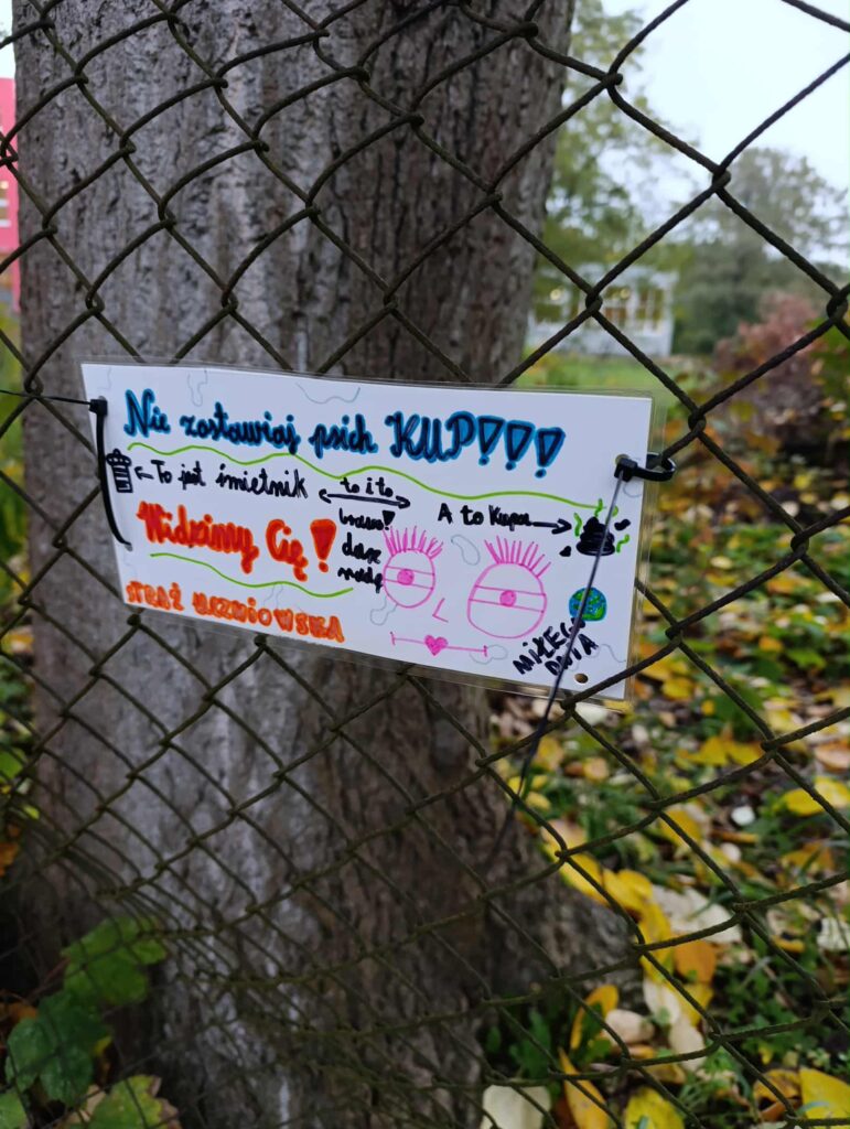 naklejona na płocie kartka z napisem nie zostawiaj psich kup