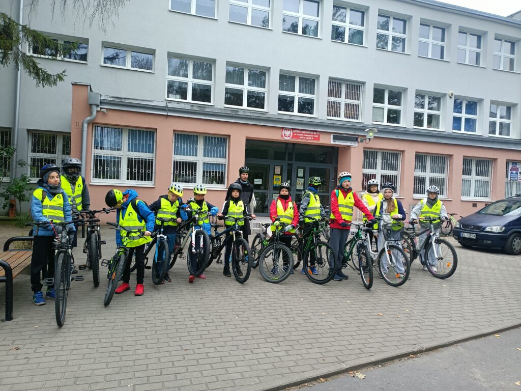 uczniowie z przewodnikiem na rowerach przed szkołą