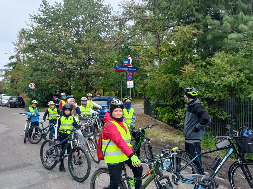 uczniowie jadą bądź stoją przy rowerach