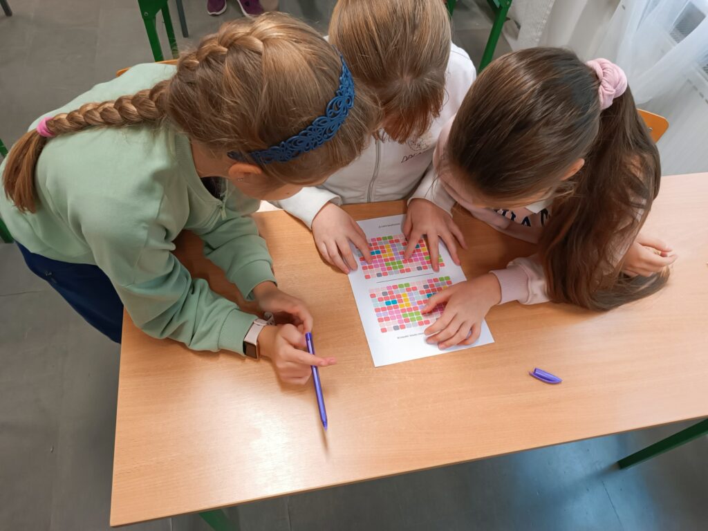 trzy dziewczynki pochylają się nad kartą pracy