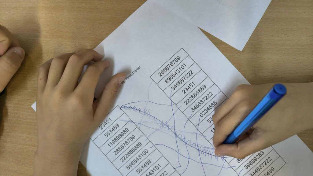 widać rączki jak rozwiązują zadanie na kartce 