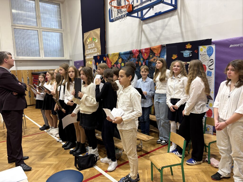 zdjęcie chóru i nauczyciela ich uczącego i prowadzącego 