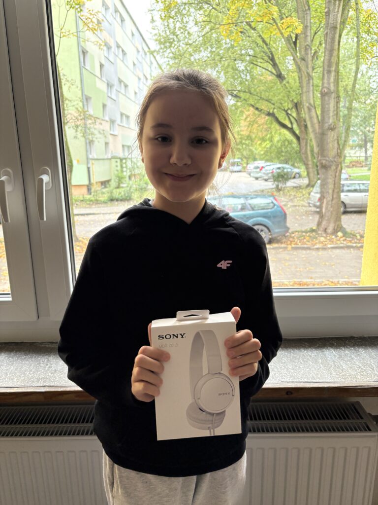 uczennica trzyma słuchawki - nagrodę.