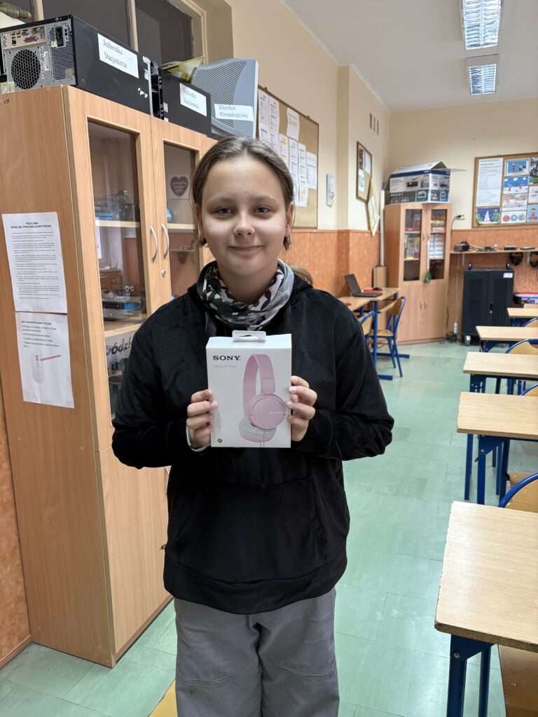 uczennica trzyma słuchawki - nagrodę.