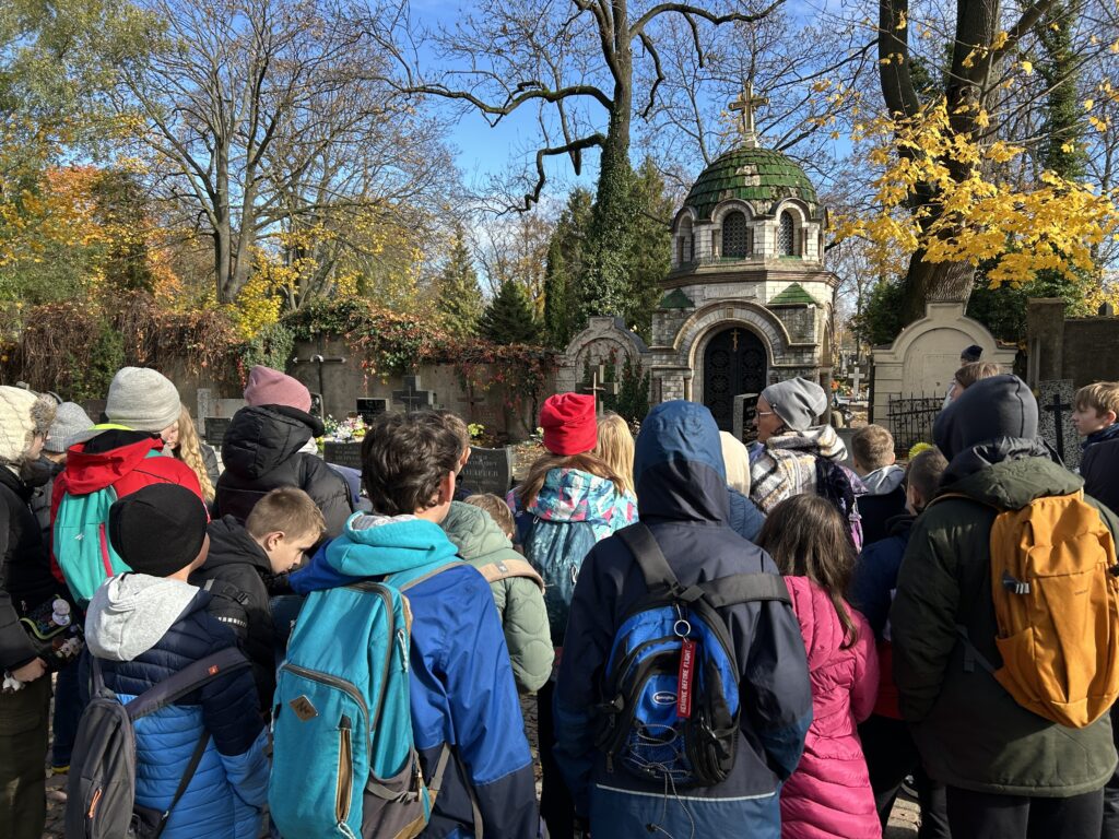 dzieci stoją tyłem do aparatu i patrzą na kolejne grobowce