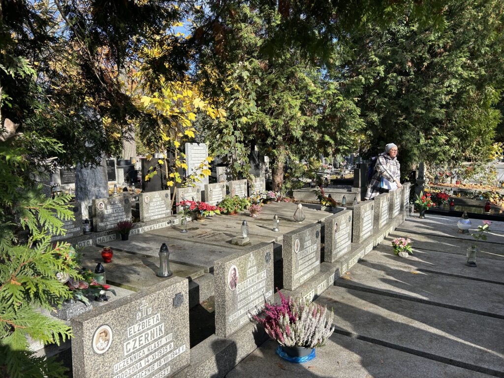 nauczycielka stoi przy grobach zmarłych harcerek i opowiada o nich historię