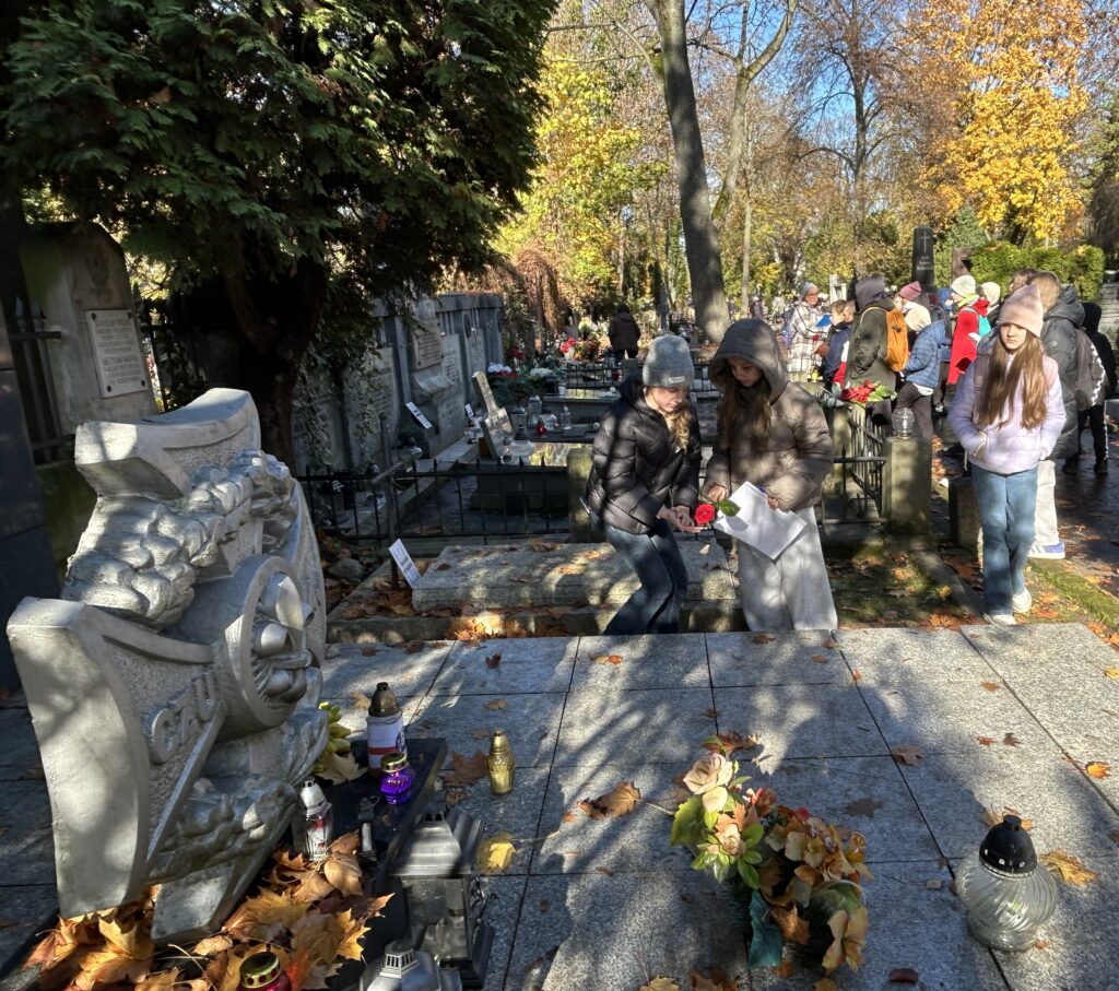dwie dziewczynki kładą różę na grobie poległych w czasie wojny harcerek (napis czuwaj)