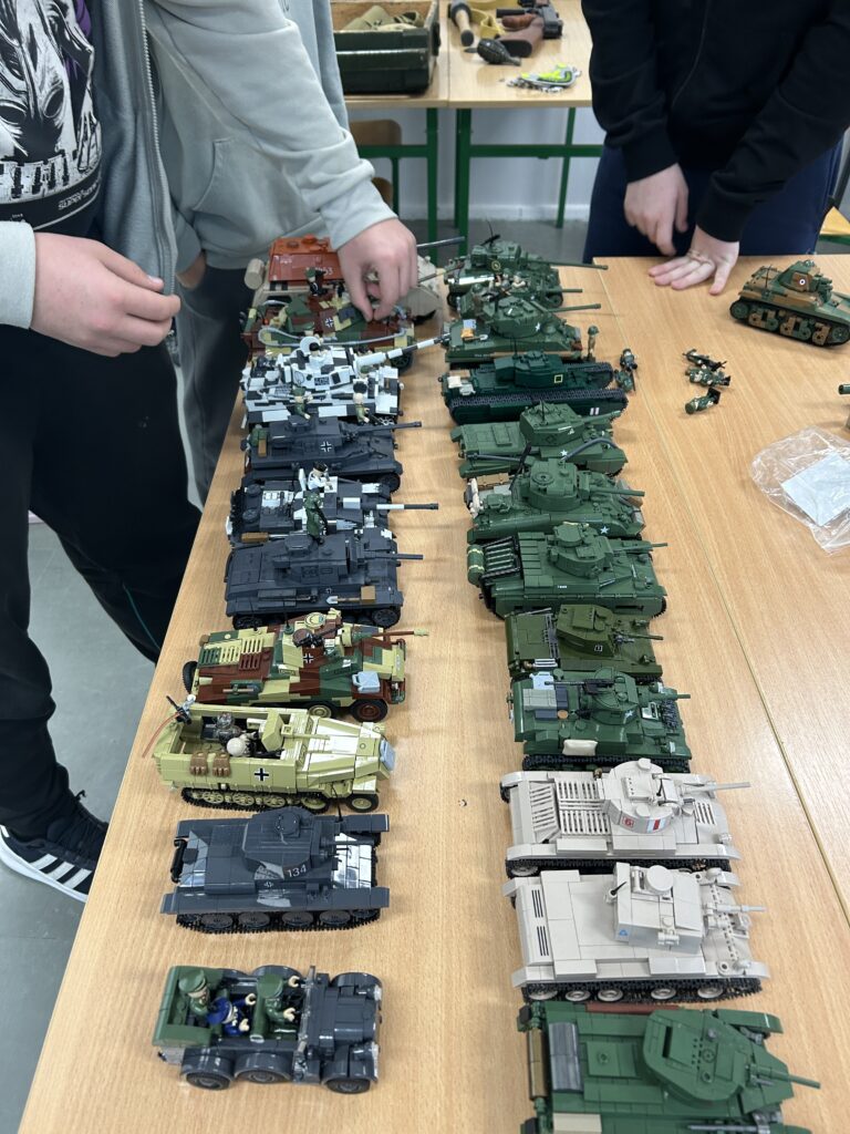 na ławce ustawione w dwóch rzędach czołgi z klocków