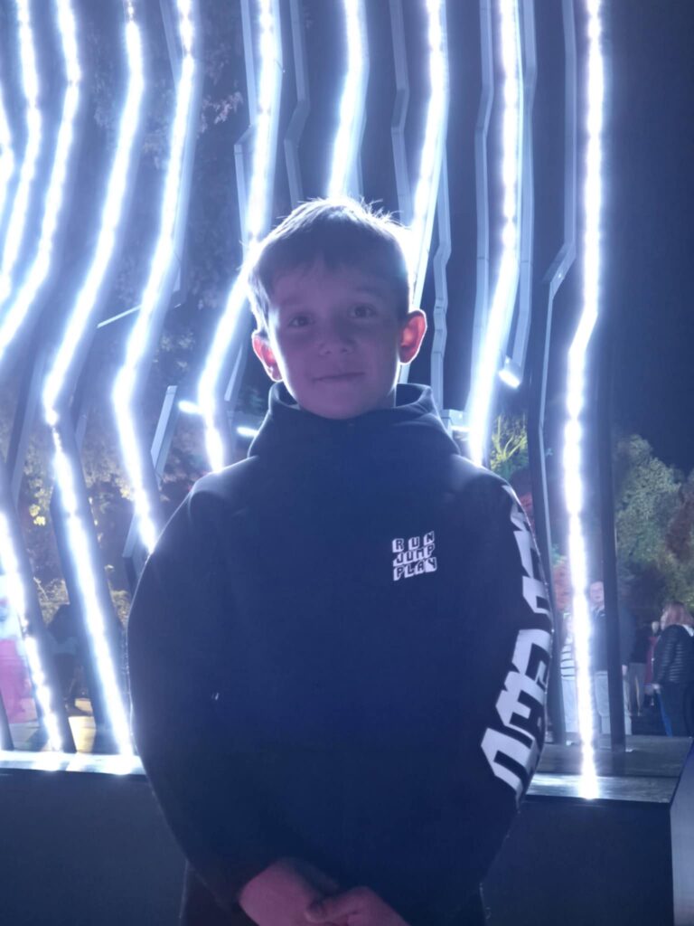 Oliwier z 4 b - chłopiec stoi na tle ciekawej, świetlnej instalacji