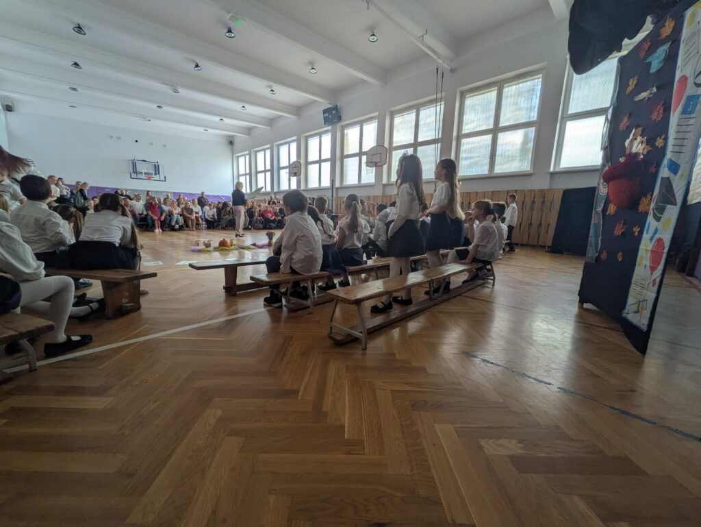 zdjęcie uczniów od tyłu, siedzą na ławeczkach