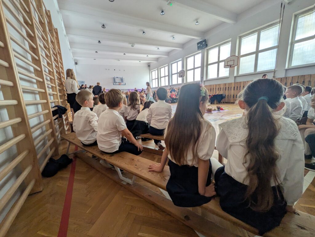 zdjęcie uczniów od tyłu, siedzą na ławeczkach