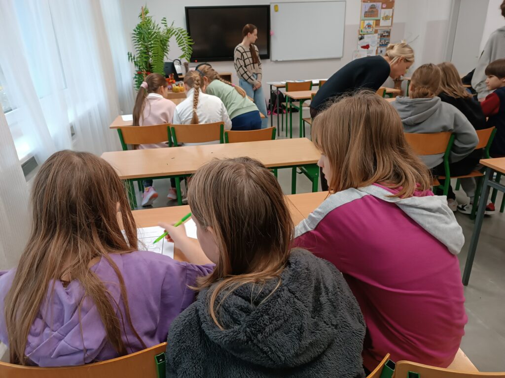 dzieci siedzące w ławkach