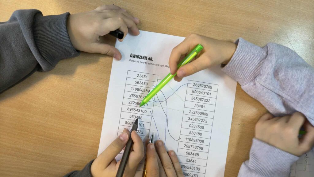 widać rączki jak rozwiązują zadanie na kartce 