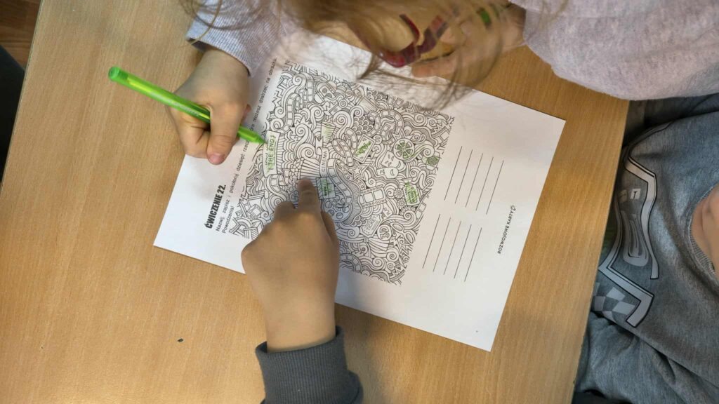 widać rączki jak rozwiązują zadanie na kartce , malują