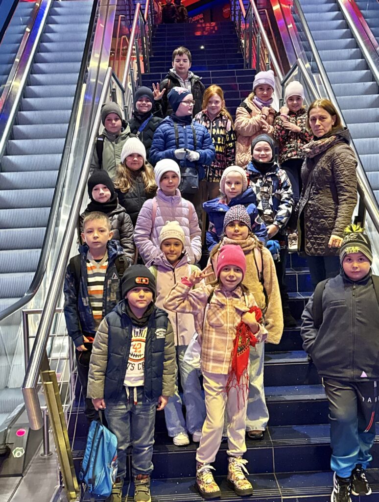 uczniowie z nauczycielem stoją między ruchomymi schodami w kinie