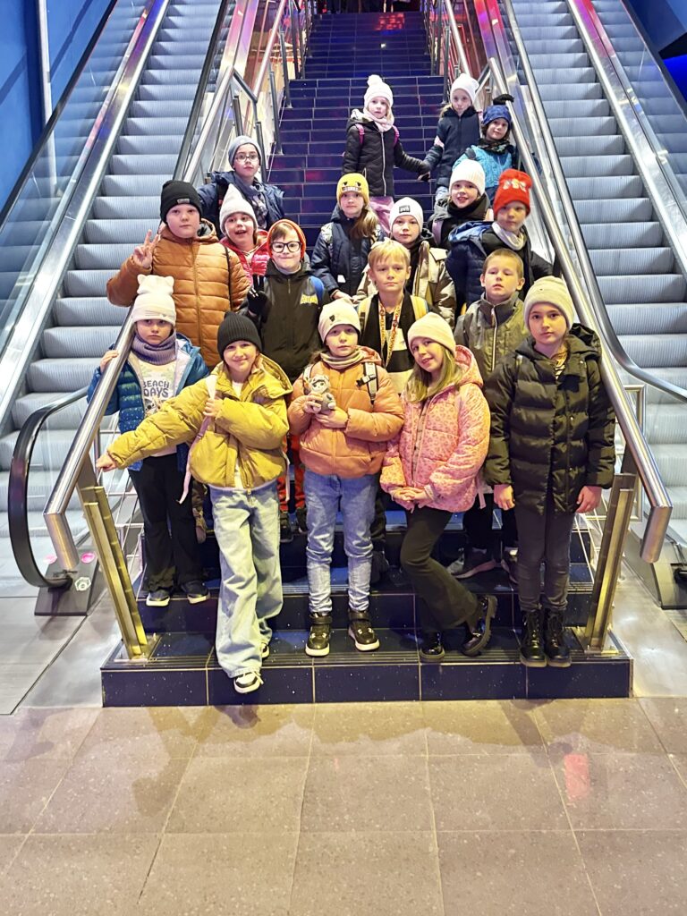 uczniowie stoją między ruchomymi schodami w kinie