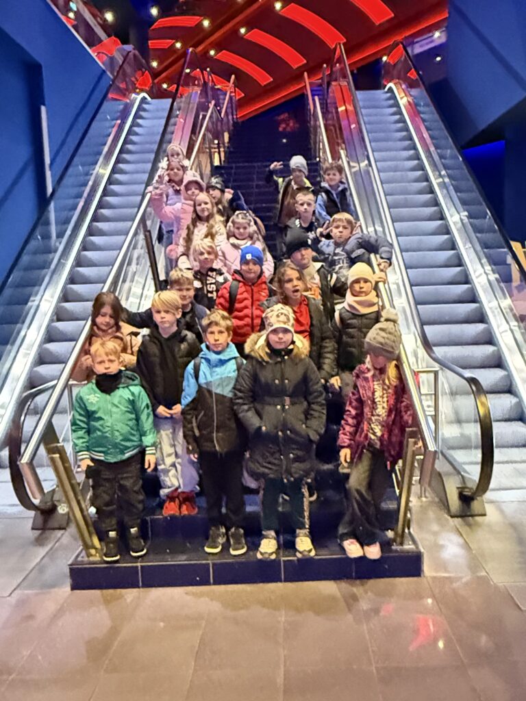 uczniowie stoją między ruchomymi schodami w kinie