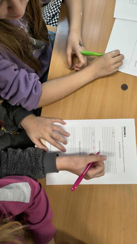 widać rączki jak rozwiązują zadanie na kartce 