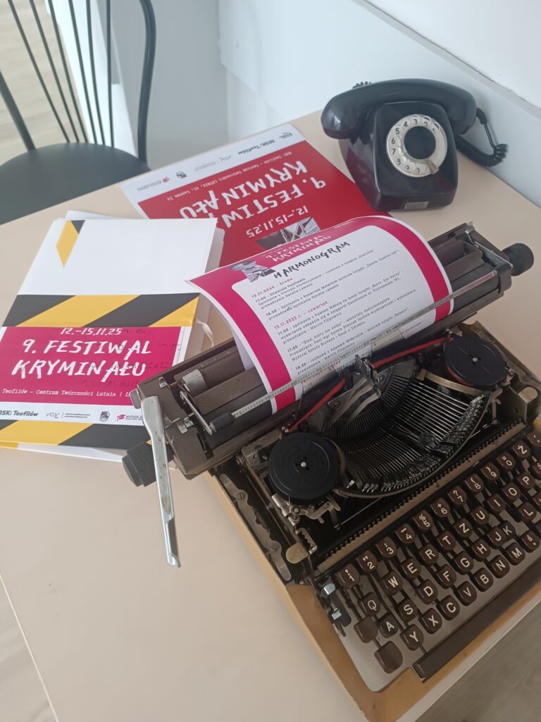 Stara maszyna do pisania na stoliku i stary telefon oraz materiały promujące i związane z 9 Festiwalem Kryminalnym