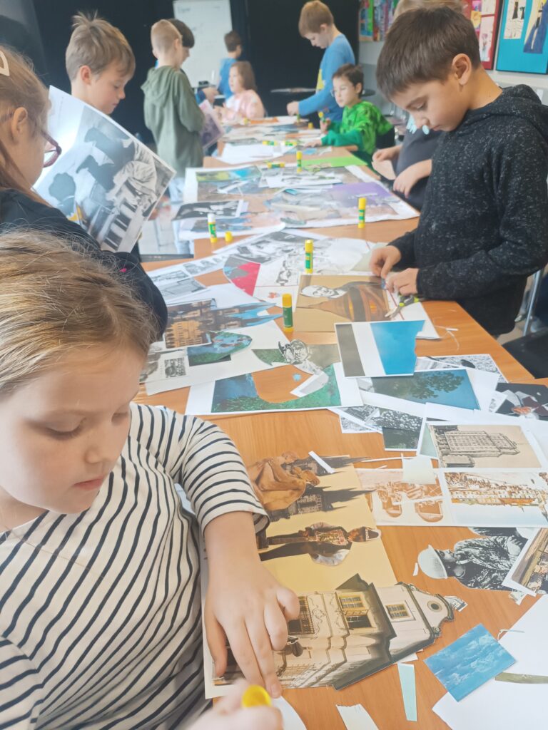 Dzieci siedzą wzdłuż długiego stołu, na którym leży dużo różnych wycinków z gazet i czasopism