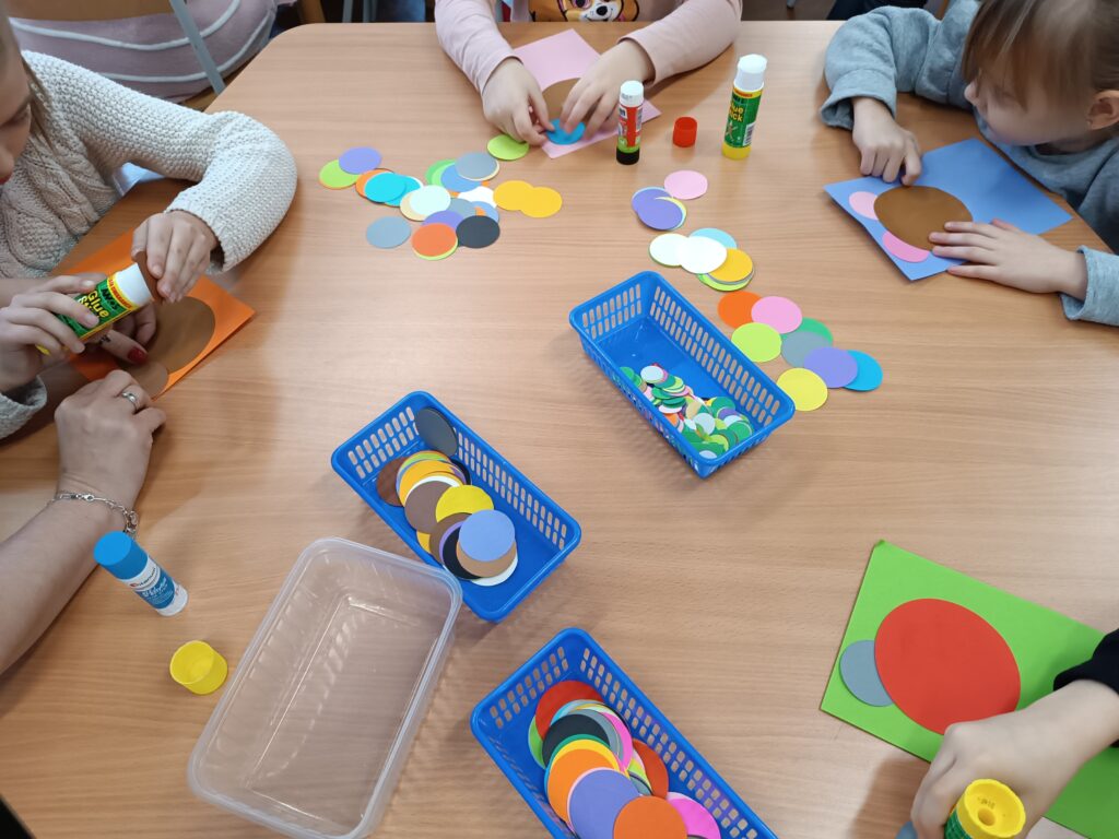 dzieci wykonują z kolorowych wycinanek i kleju portrety misiów