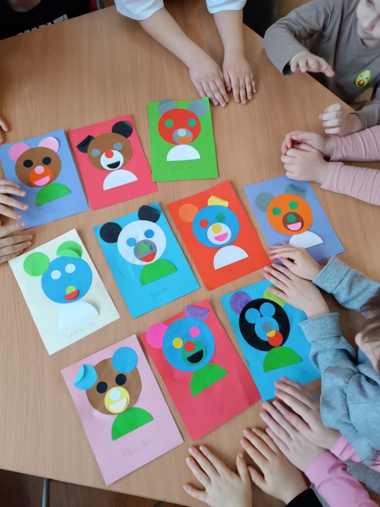 zdjęcie przedstawia na ławce leżące prace dzieci- wyklejone misie 