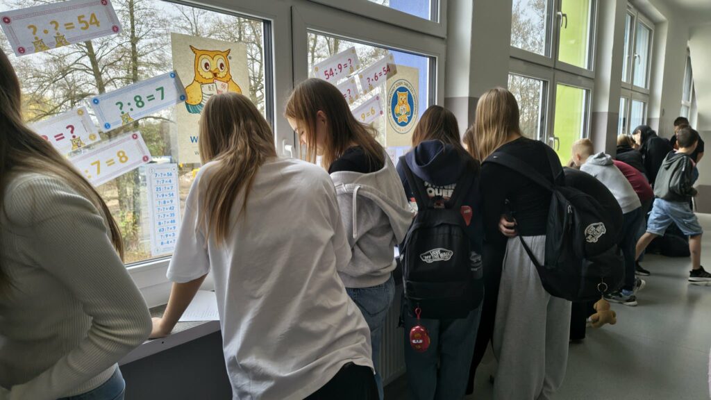 widzimy dzieci które  wykonują karty pracy na parapetach 