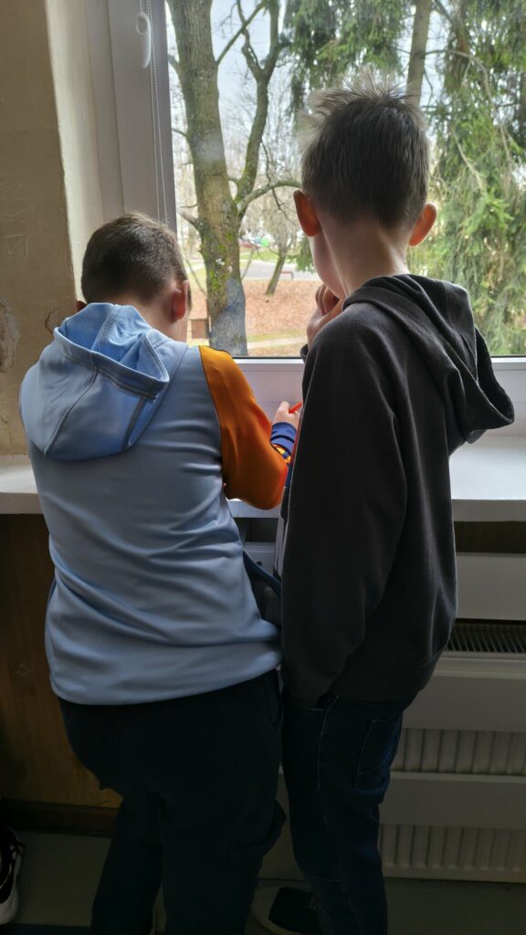 widzimy dzieci które  wykonują karty pracy na parapetach 