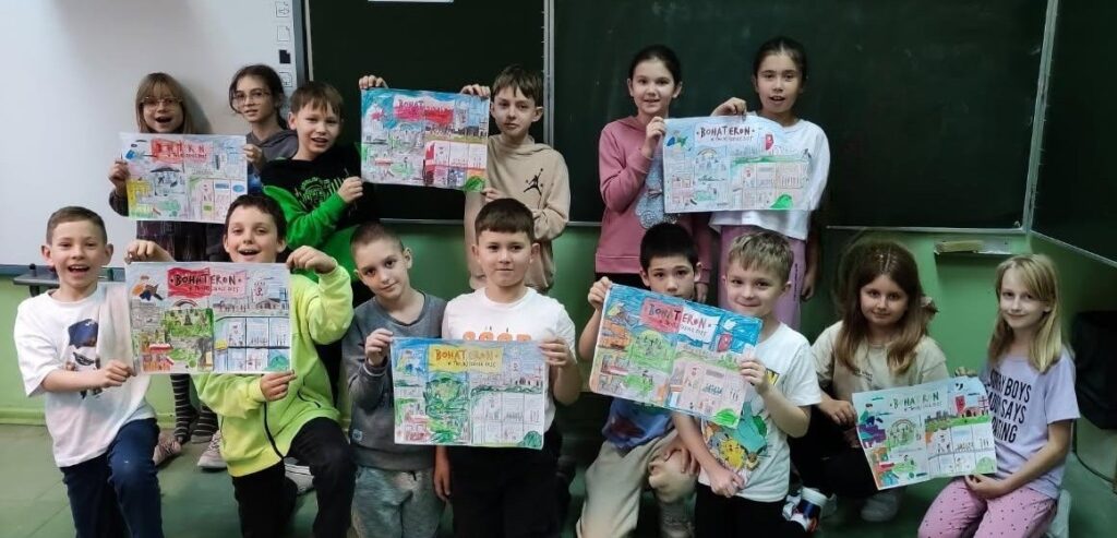 Uczniowie klasy 3 c pozują do zdjęcia. Są uśmiechnięci. W rękach trzymają plakaty z napisem BohaterON. Na plakatach narysowali ważne wydarzenia, historię Powstania Warszawskiego