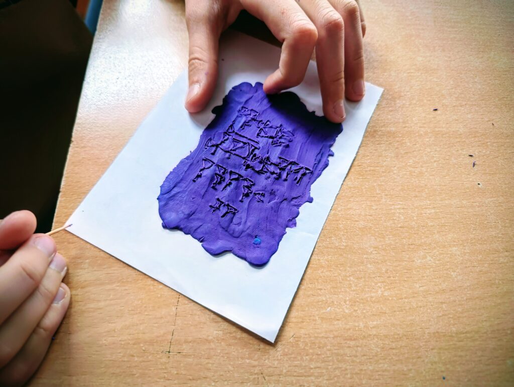 zdjęcie przedstawia wycięcia w plastelinie jakieś znaki