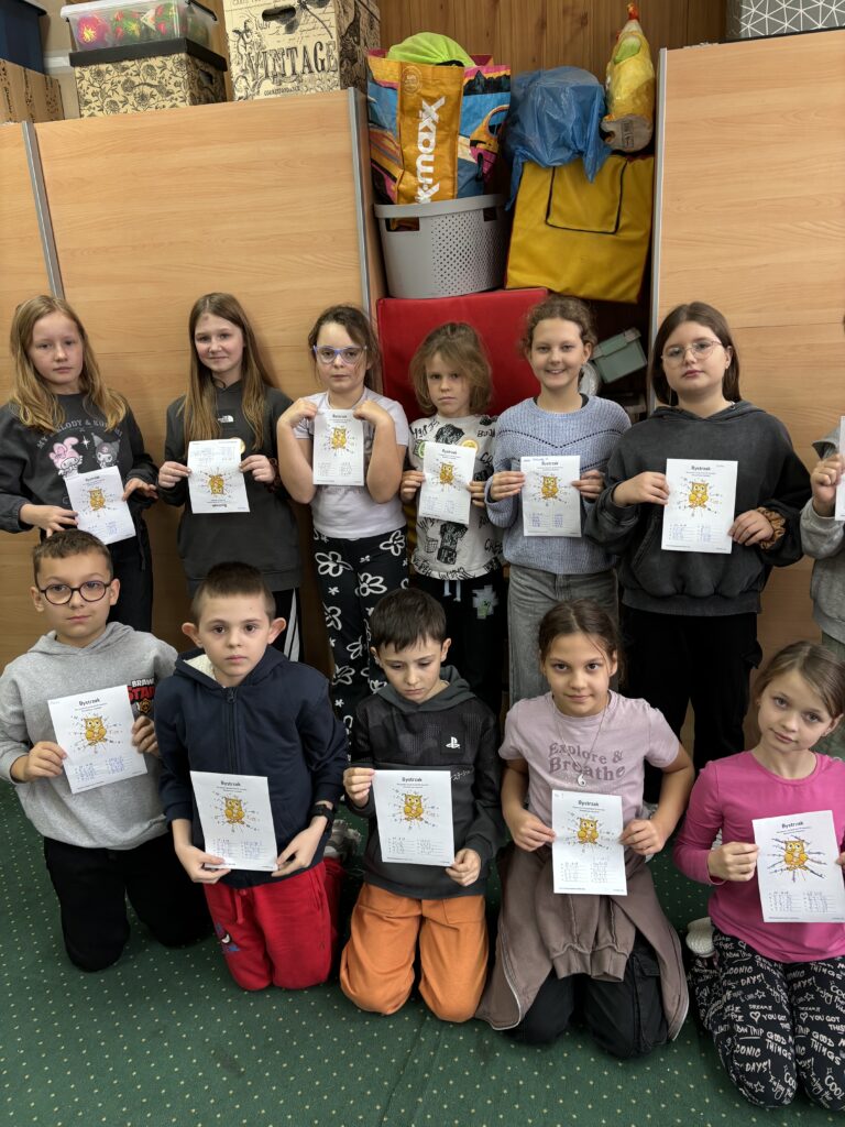 zdjęcie jednej z klas, dzieci prezentują wykonane przez siebie zadania związane z tabliczką mnożenia