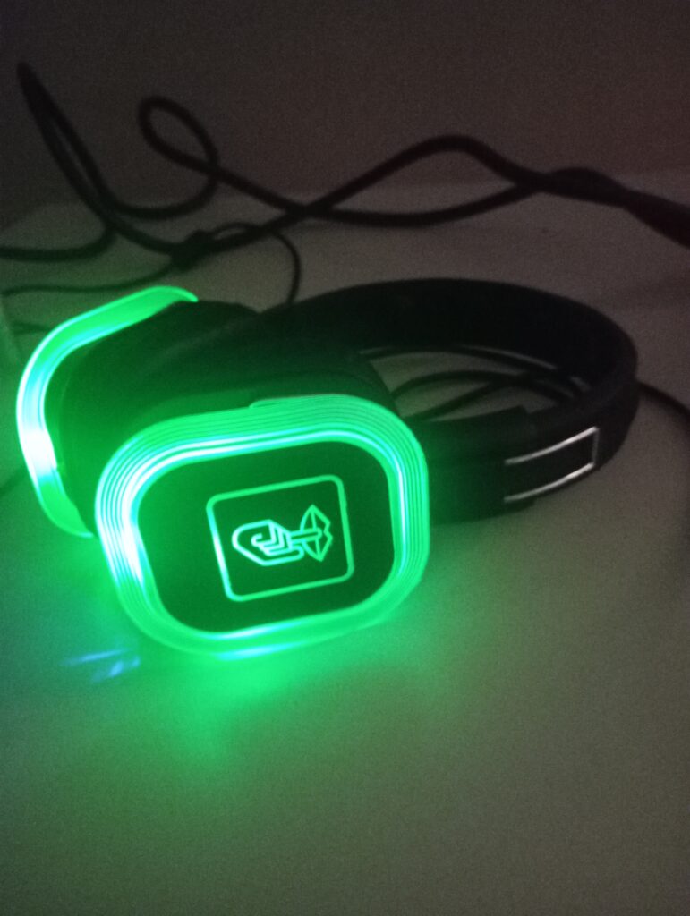 Czarne, świecące na zielono słuchawki leżą na białej ławce