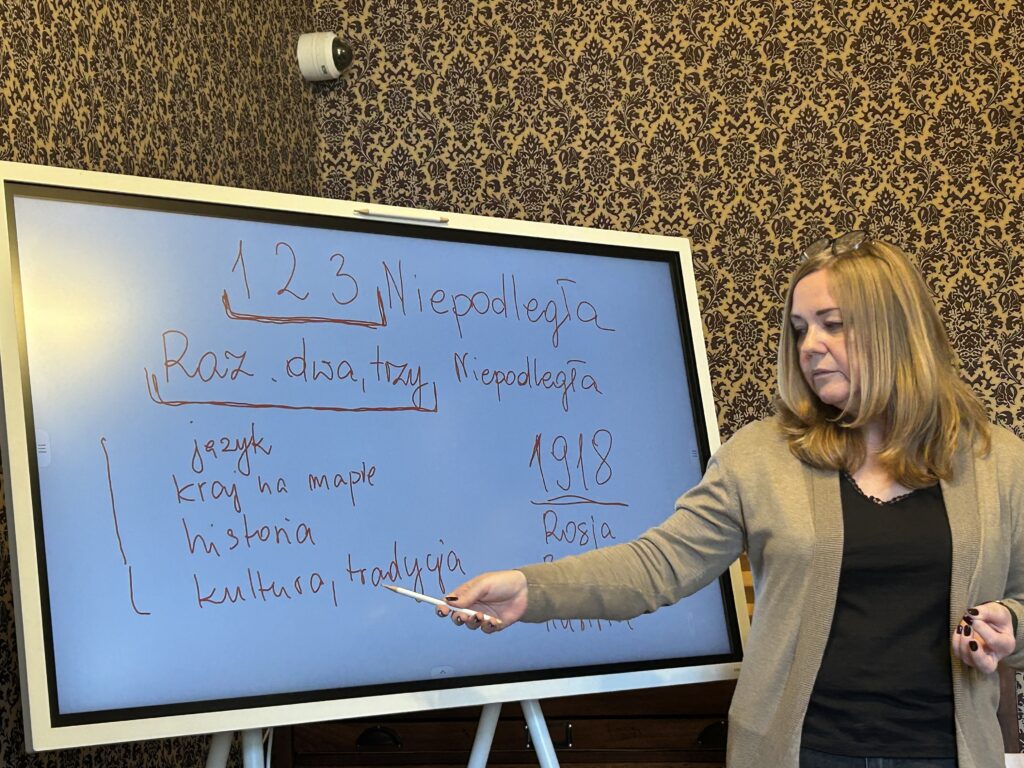 w Muzeum Bibuła, pani edukatorka zapisała na tablicy temat 1, 2, 3  Niepodległa oraz słowa:  język, kraj na mapie, historia, kultura tradycja oraz rok 1918