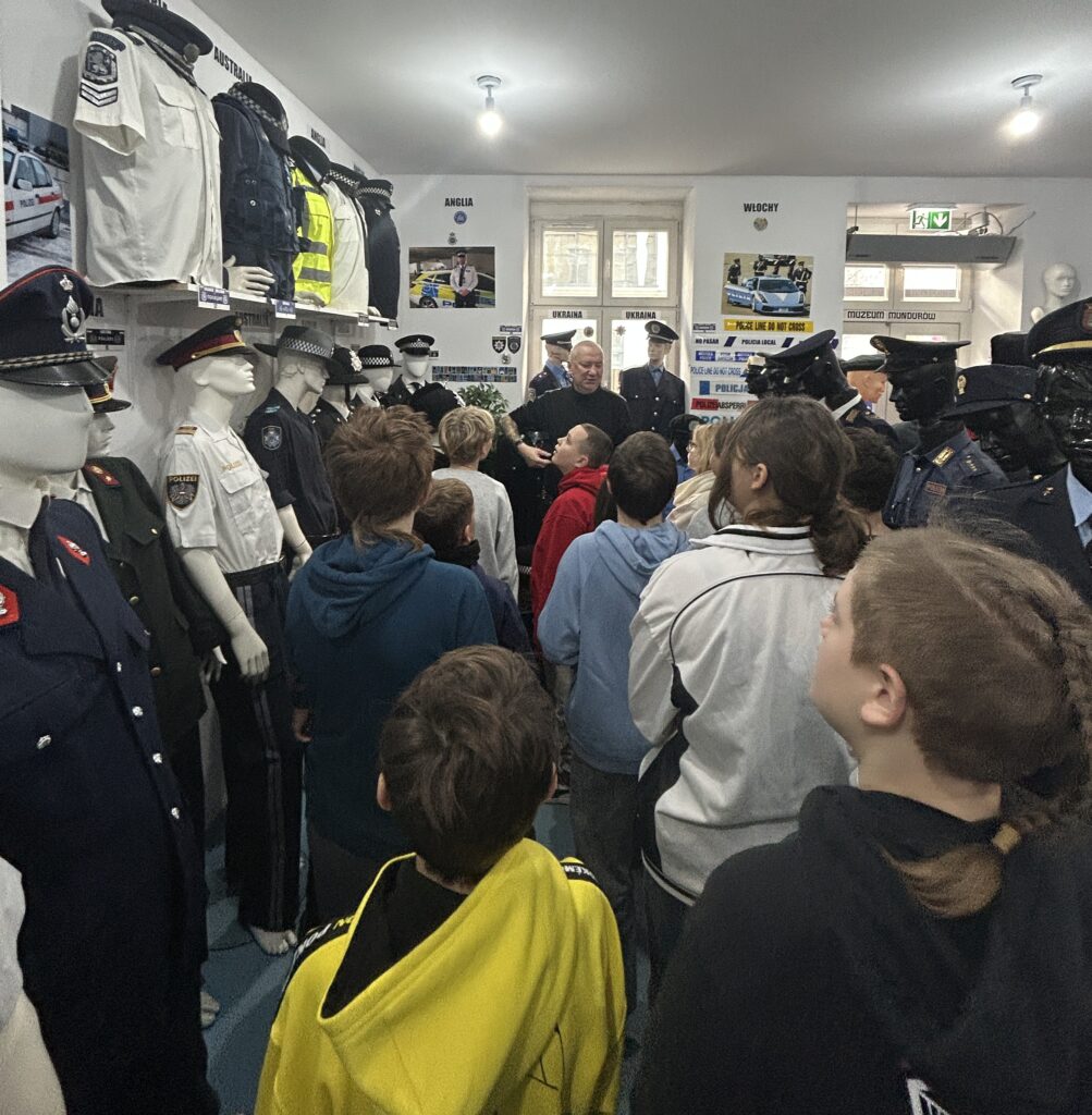 dzieci oglądają sale w której stoją manekiny w mundurach różnych państw, w głębi właściciel muzeum opowiada o mundurach