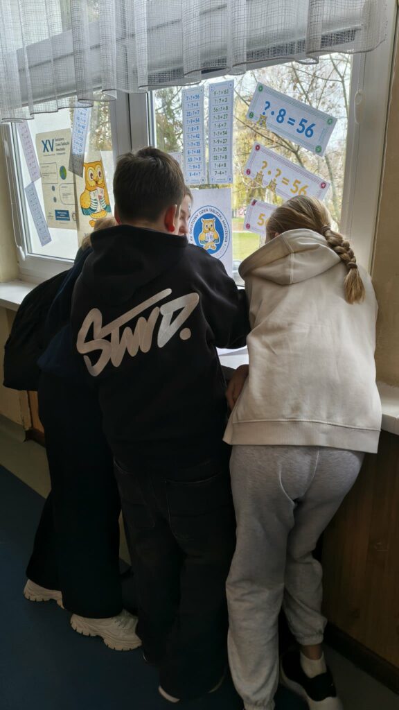 widzimy dzieci które  wykonują karty pracy na parapetach 