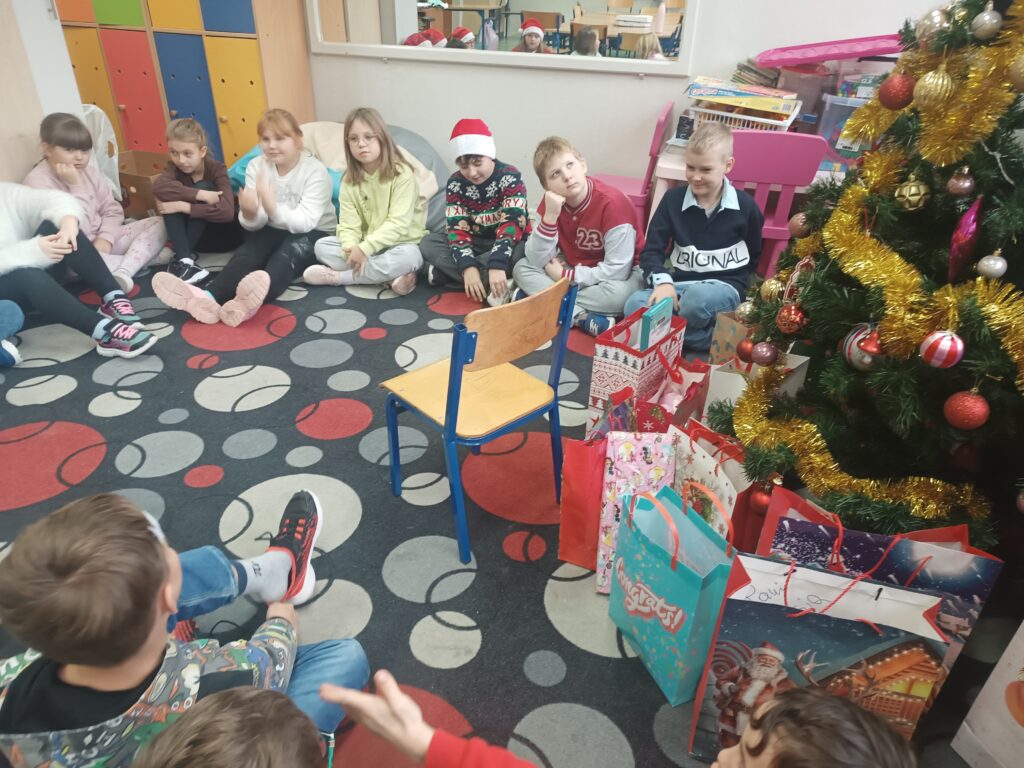 dzieci siedzą pod choinką i czekają na prezenty