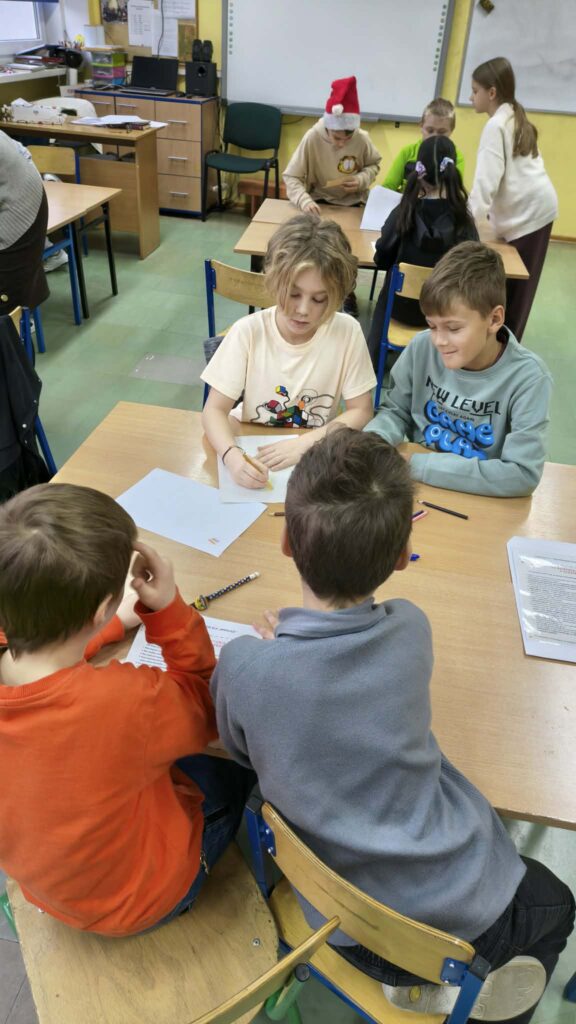 zdjęcie na którym widać dzieci podzielone na grupy rozwiązujące karty pracy w zespołach