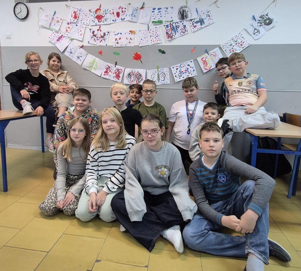 Uczniowie na zdjęciu grupowym na tle swoich prac